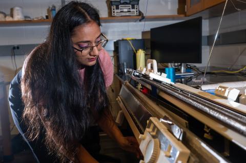 Former Matsumoto Group member Krishma Singal operates a knitting machine used to create fabric samples for a previous study. Singal recently graduated from Georgia Tech with her Ph.D. (Photo Credit: Allison Carter)